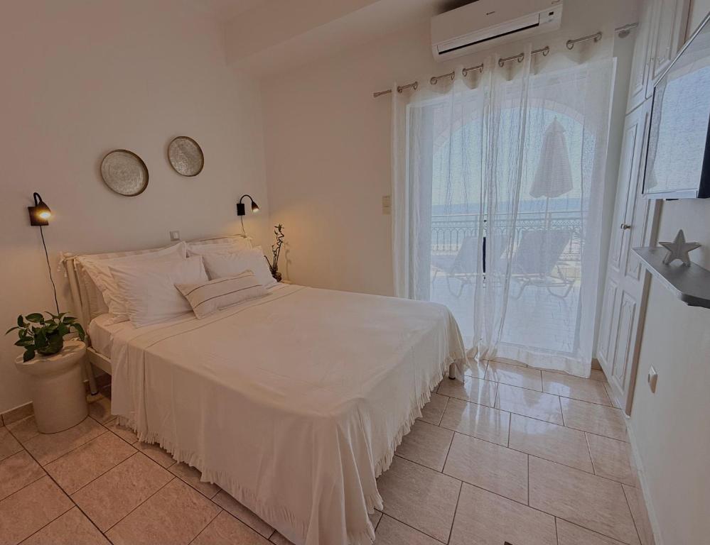 a white bedroom with a bed and a window at Selini Apartments Mani in Agios Nikolaos