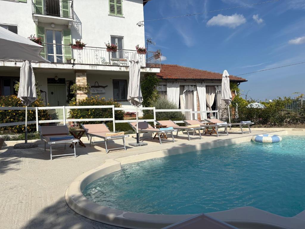 a swimming pool in front of a house with chairs and a building at Cà Bianca in Casorzo