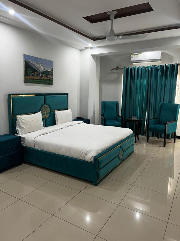 a bedroom with a large bed and blue chairs at We Hotels in Islamabad
