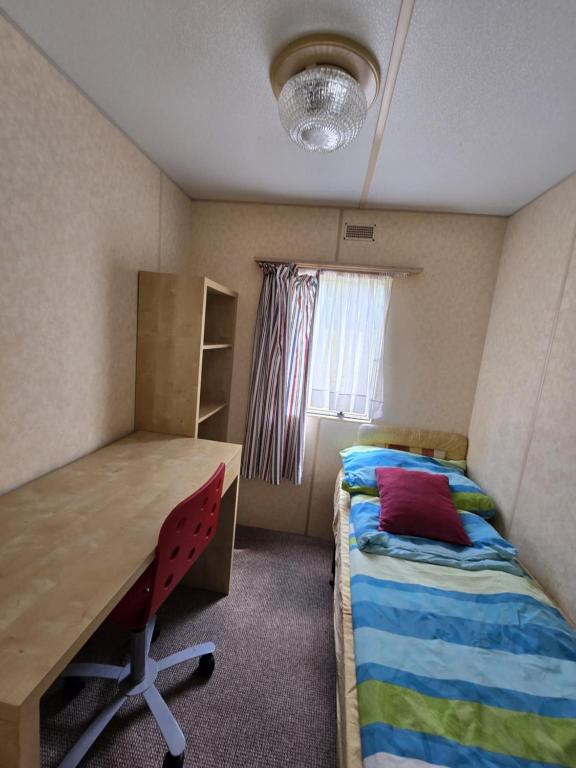 a small room with a bed and a desk and a table at Domki u Agi in Głęboczek