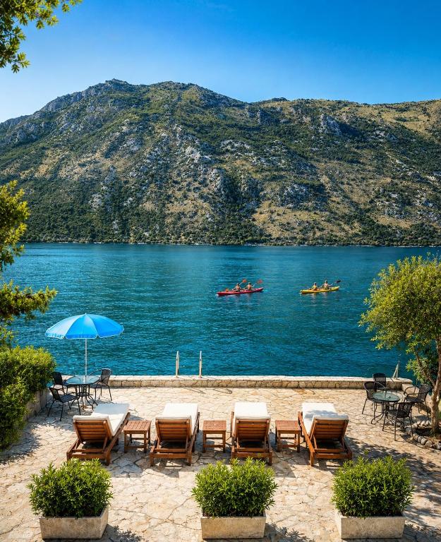 a beach with tables and chairs and boats in the water at Stonehouse Kotor Bay in Kotor