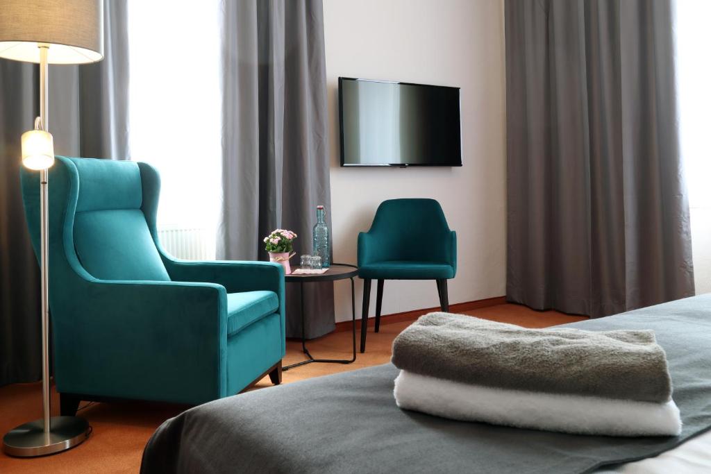 a hotel room with two chairs and a tv at Hotel Sächsischer Hof in Pirna