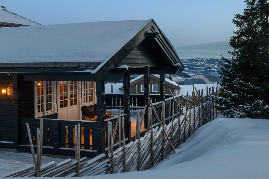 a cabin in the snow with a fence at High-standard cabin with jacuzzi & stunning views in Øyer