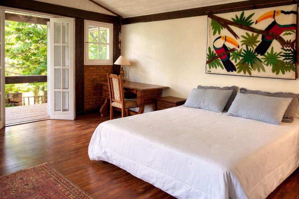 a bedroom with a bed and a table and a desk at Fazenda Vista Soberba in Nova Friburgo