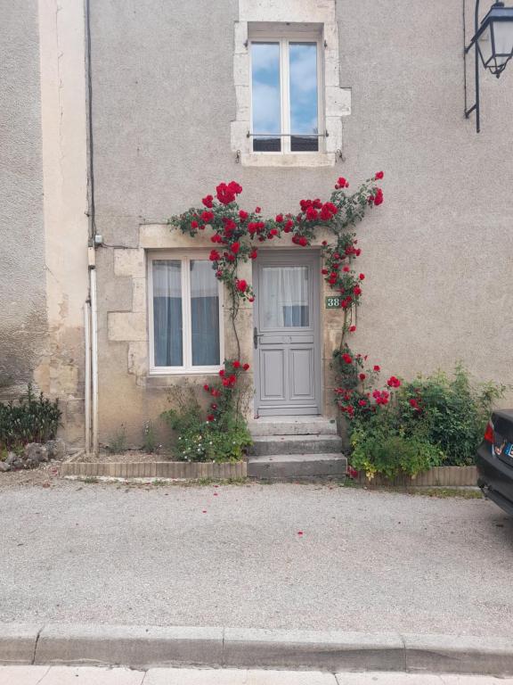 a house with a door with red flowers on it at Le lit de la SEINE in Saint-Seine-lʼAbbaye