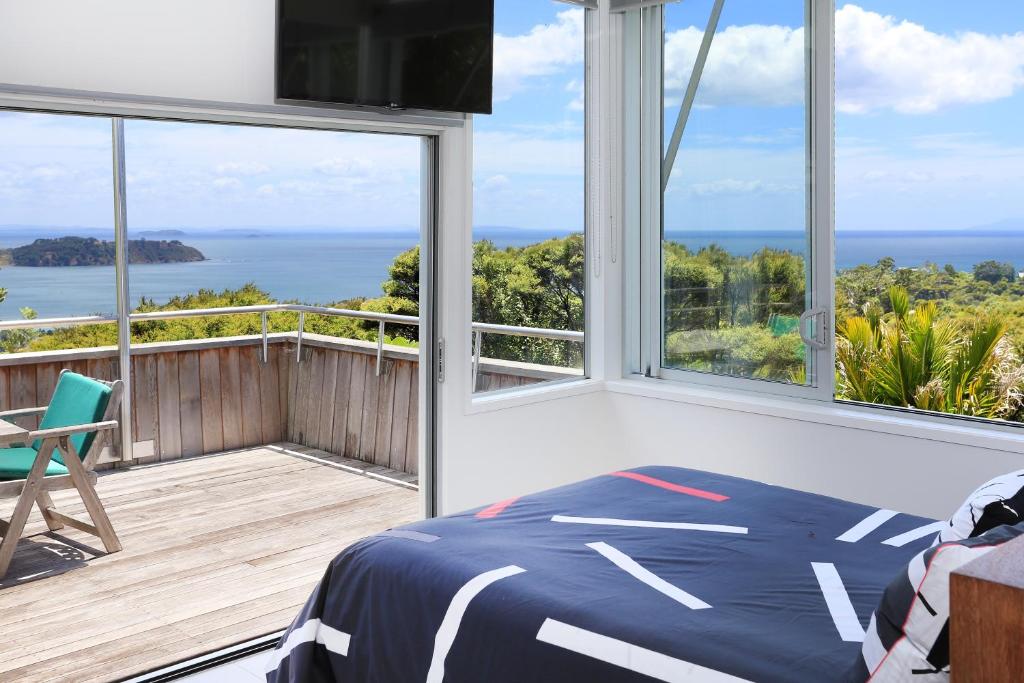 a bedroom with a bed and views of the ocean at The Nikau Loft in Onetangi