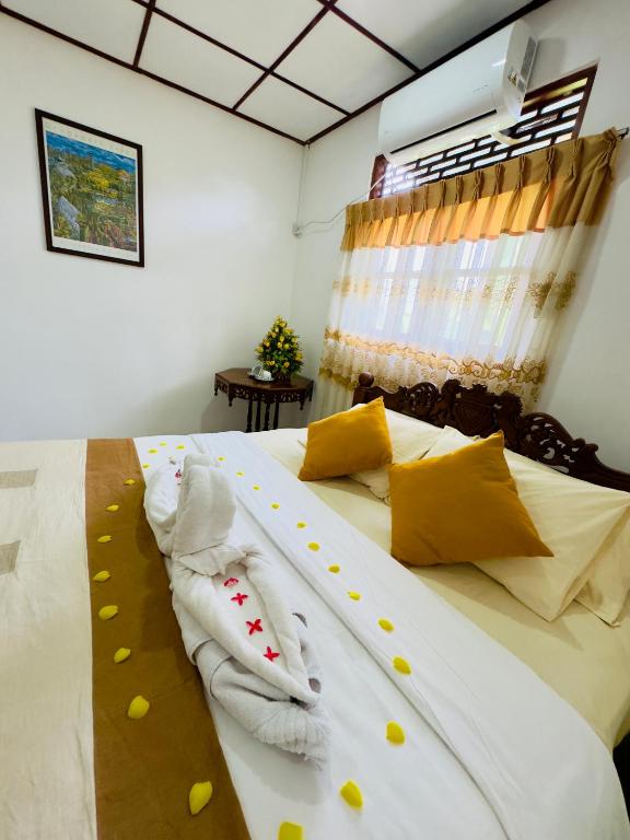 a bedroom with a bed with yellow and white pillows at The Travellers Rest in Katunayaka