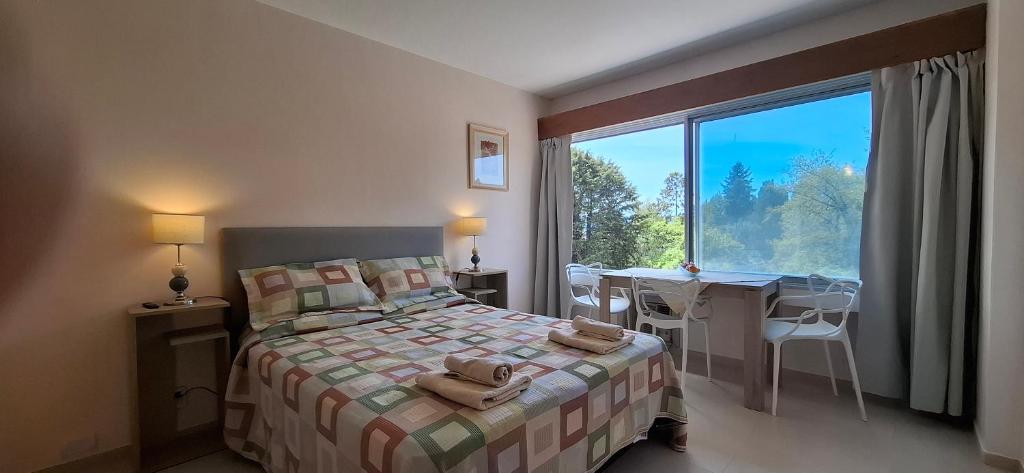 a bedroom with a bed and a desk and a window at El encanto del lago in San Carlos de Bariloche