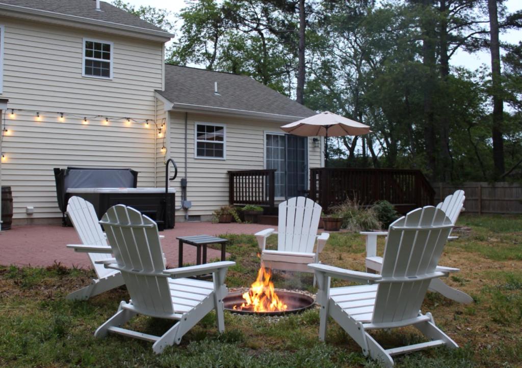 four white chairs around a fire pit in a yard at Beach Hoppers' Hideaway in Cape Charles