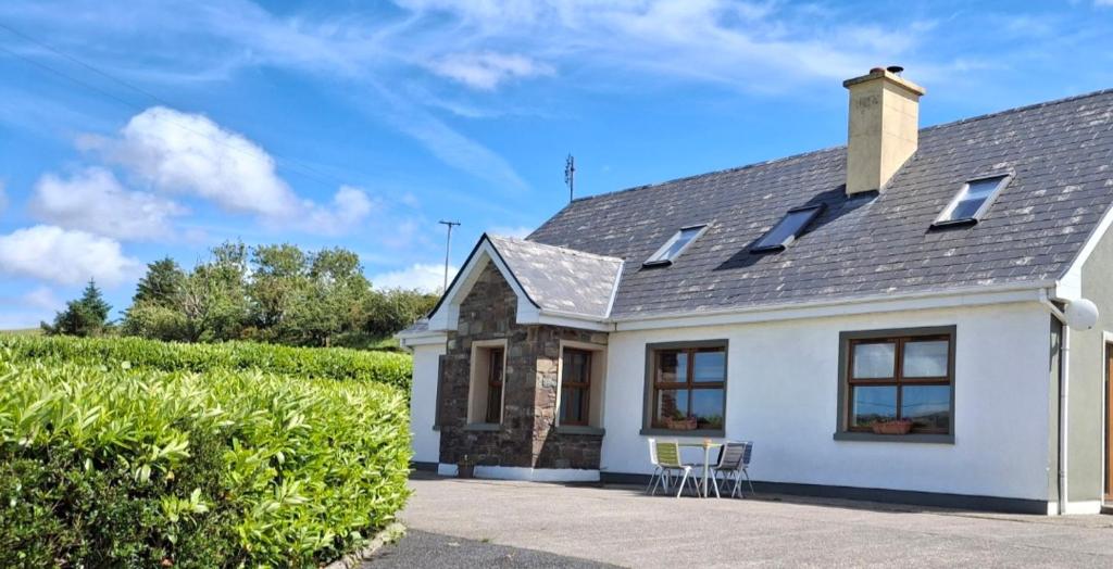 a white house with two chairs and a hedge at Wooly Lodge in Westport