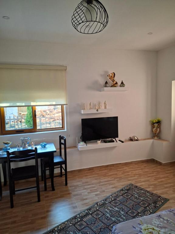 a living room with a table and a television at Laboti Quiet Room in Librazhd