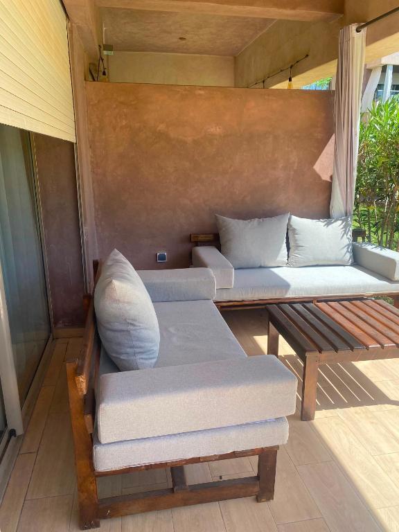 a porch with two beds and a wooden bench at Prestigia Marrakech in Inezgane