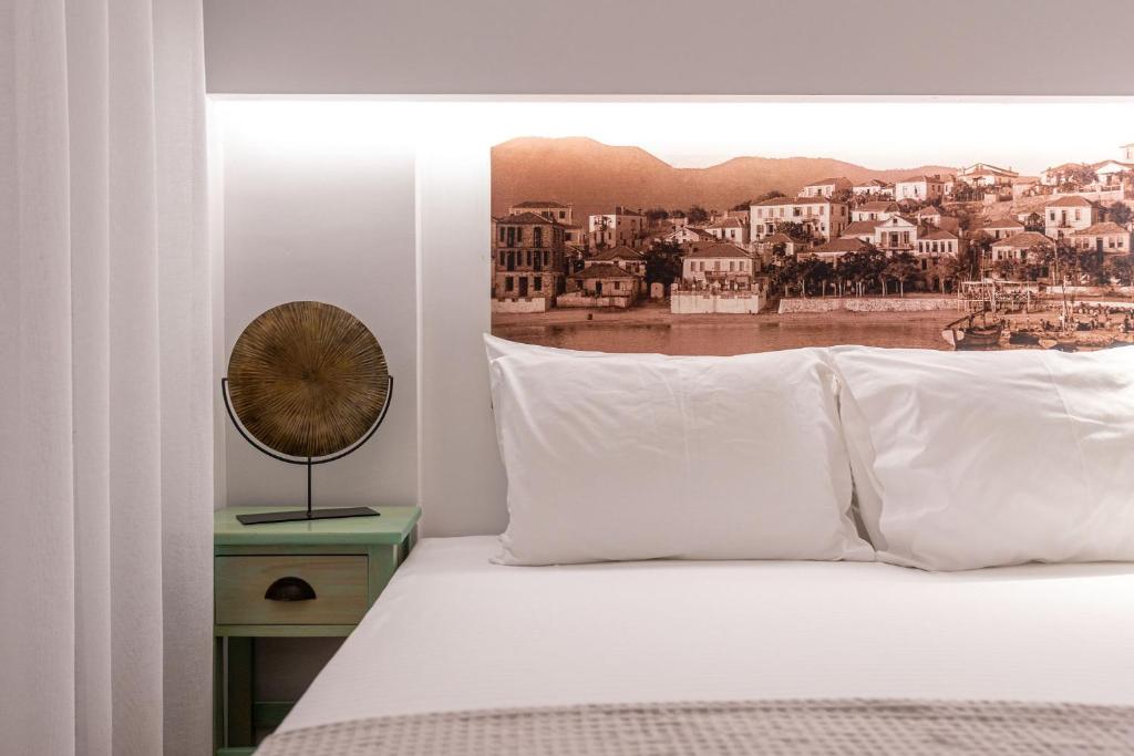 a bed with white pillows and a clock on a night stand at Limenaria Beach in Limenaria