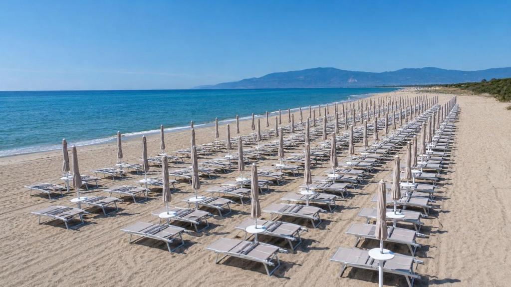 a long line of chairs and umbrellas on a beach at Caladune Resort in Pizzo