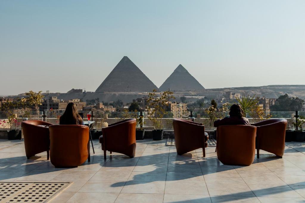 two people sitting in chairs looking at the pyramids at Hotel Comfort Giza in Cairo