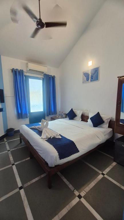 a bedroom with a large bed with a ceiling fan at Secret kitchen rooms in Candolim
