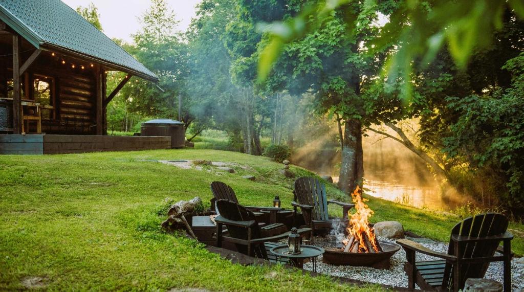 a fire pit in a yard next to a cabin at River House in Nītaure