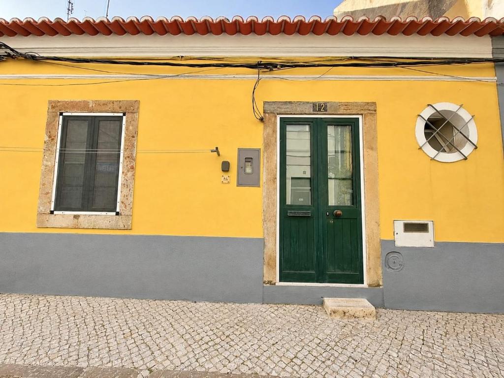 a yellow building with a green door and windows at Casa da Anunciada | Old Town in Setúbal