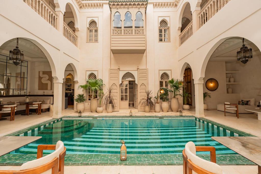 an indoor pool in a building with tables and chairs at Maison Zamane in Marrakesh