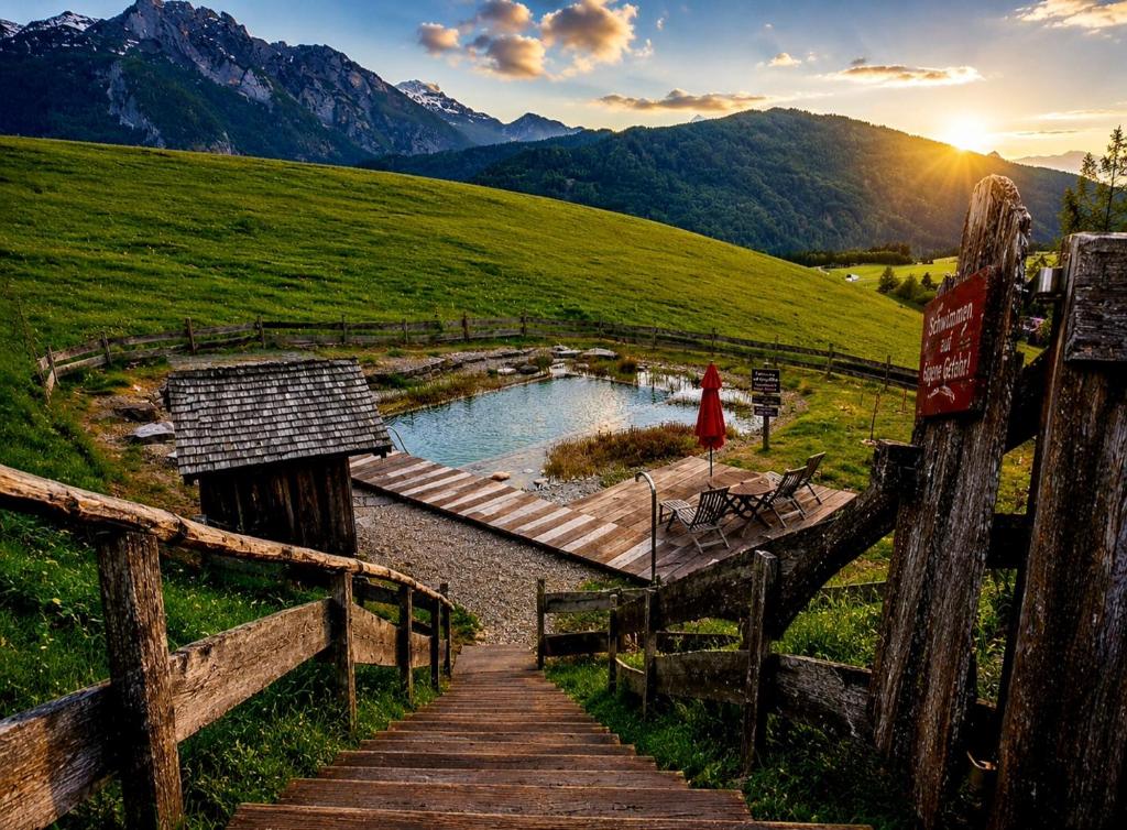 a woman walking down a wooden path towards a pond in a field at Sonnleit'n Zimmer 7 in Abtenau