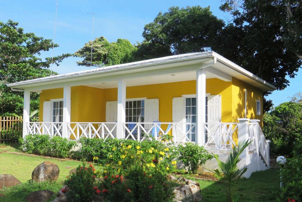 une maison jaune avec des parures blanches dans une cour dans l'établissement Sunhill Villa, à Îles du Maïs