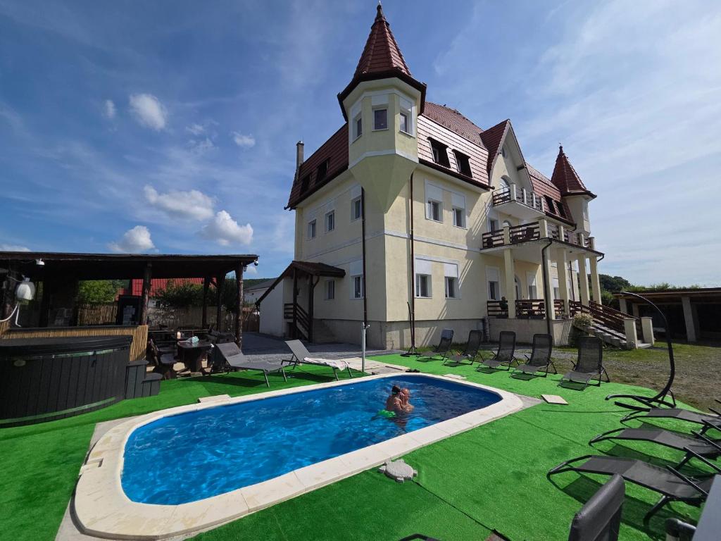 a person in a swimming pool in front of a house at Castle Csányi in Livezeni