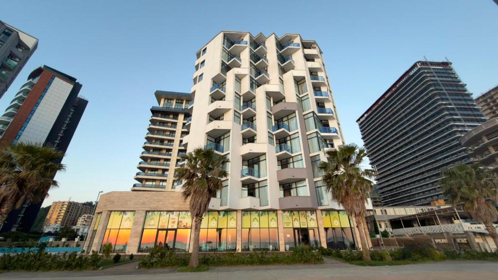 a tall white building with palm trees in front of it at Pano Hotel in Gonio