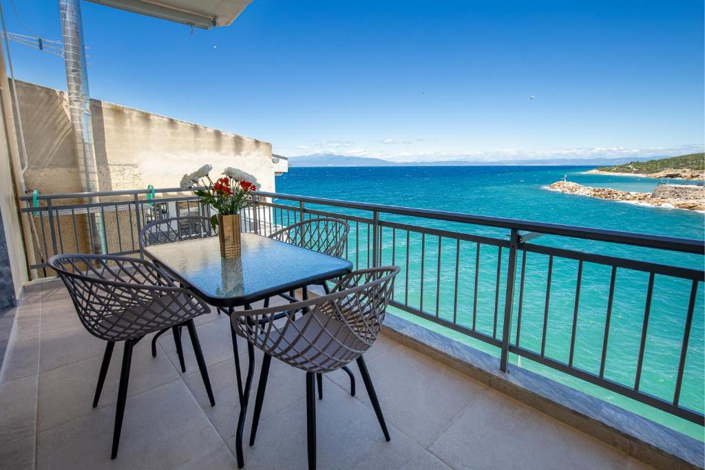 a table and chairs on a balcony overlooking the water at Sea U - Apartment in Skala Marion