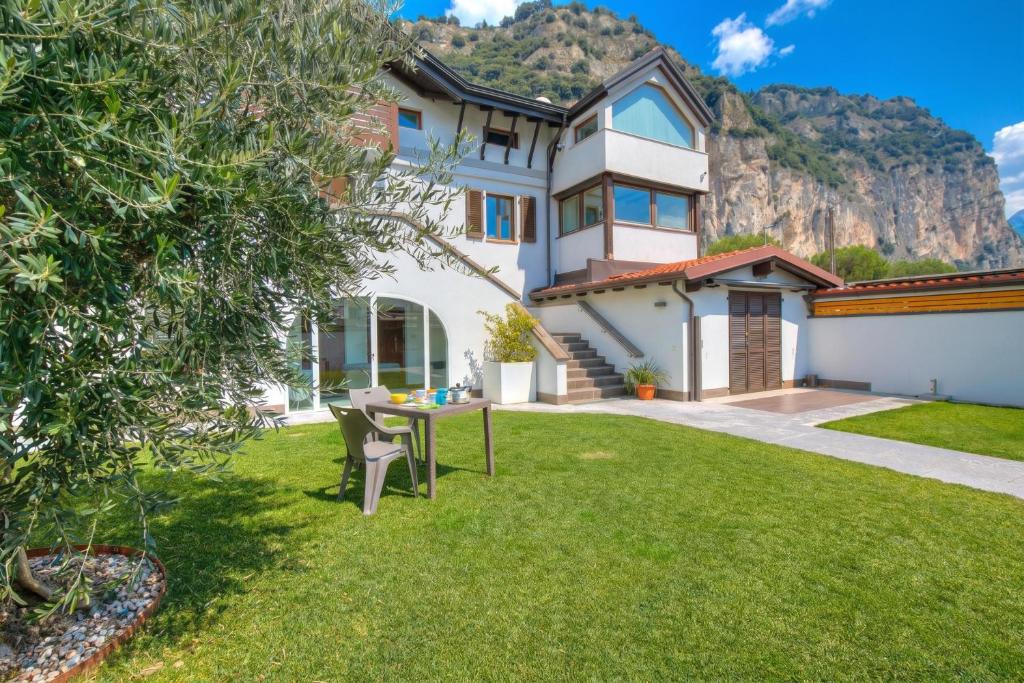 a house with a table in a yard with a mountain at Torbole Lake Front - Happy Rentals in Arco