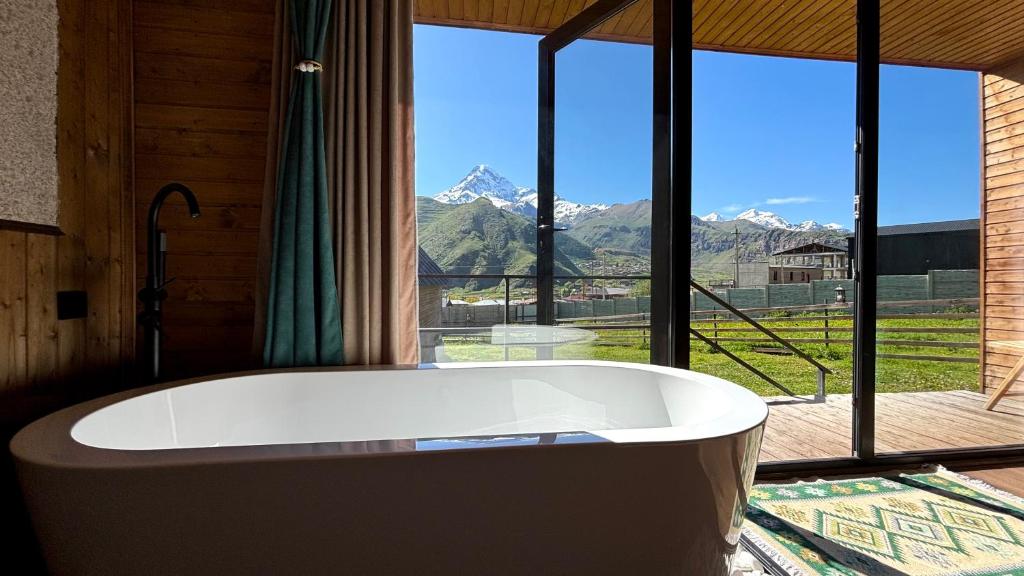 a bath tub in a room with a view of mountains at Mtaura Cabins in Kazbegi