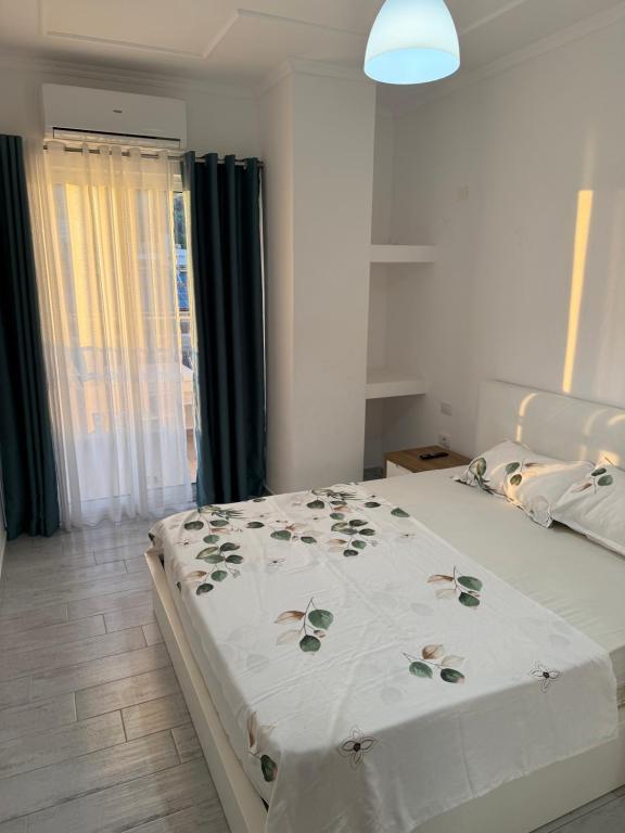 a bedroom with a white bed with a floral bedspread at Marina in Shëngjin