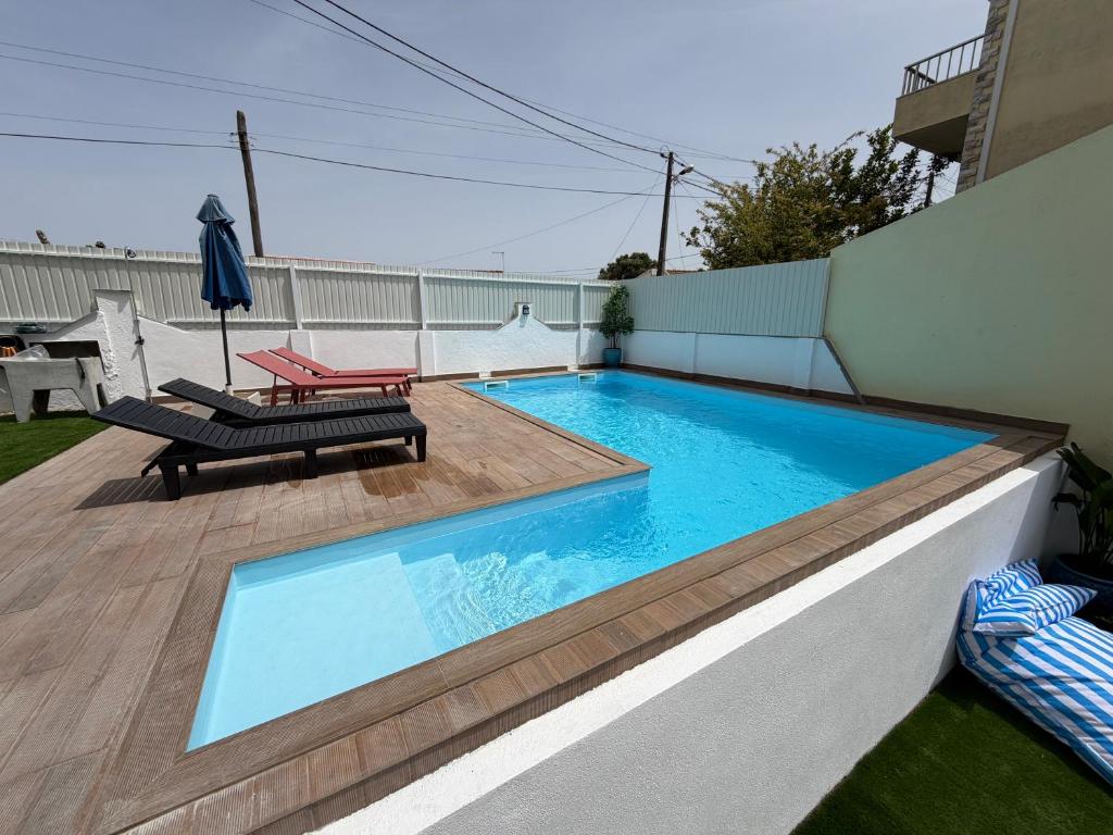 a swimming pool in a backyard with a wooden deck at Moradia com escada, Jardim e piscina, 3Kms Praia in Almada