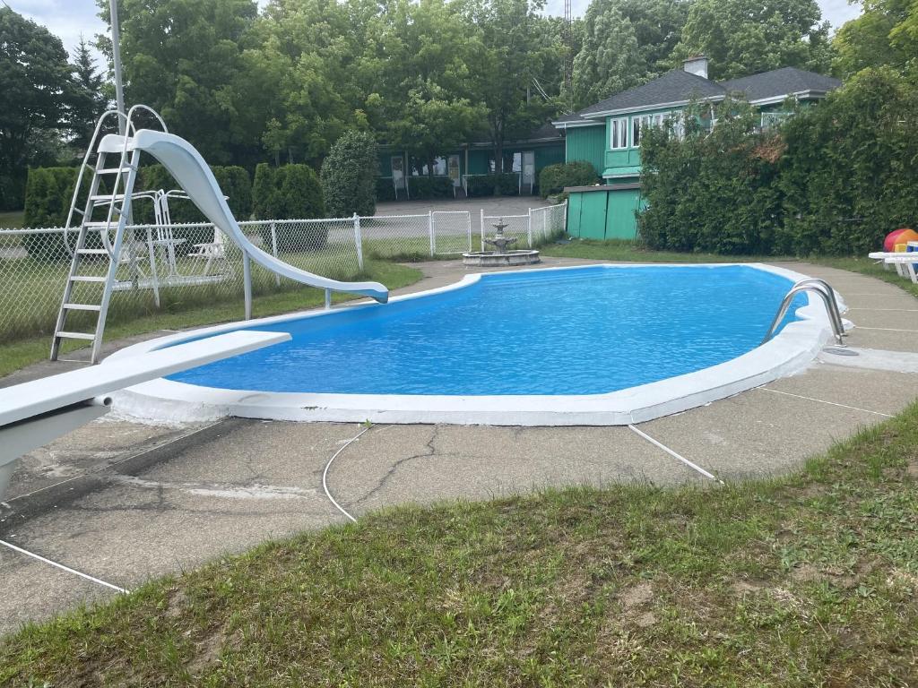 a swimming pool with a slide in a yard at Motel Le Voyageur in Saint-Jérôme