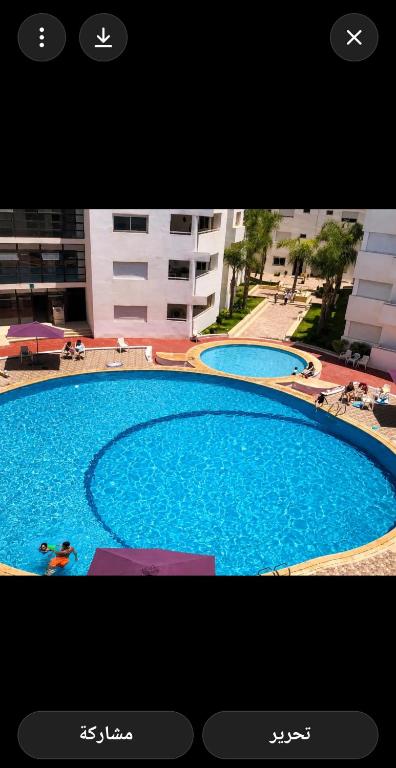 a picture of a large blue swimming pool at jardin de raisin in Bouznika