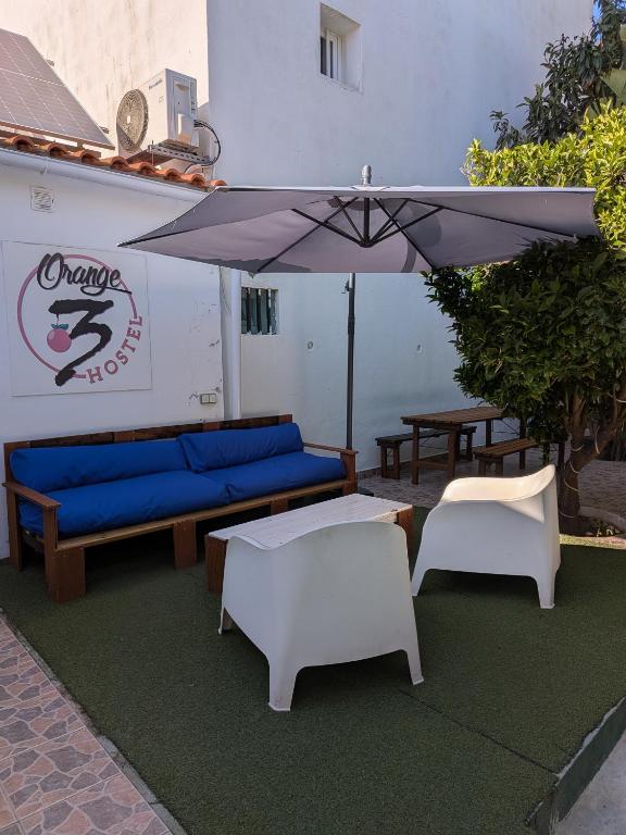 a patio with two couches and an umbrella at Orange3 Hostel in Lagos