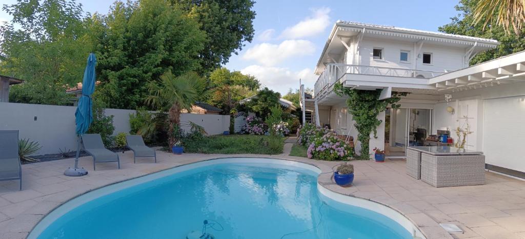 a swimming pool in front of a house at La Nomade in Andernos-les-Bains