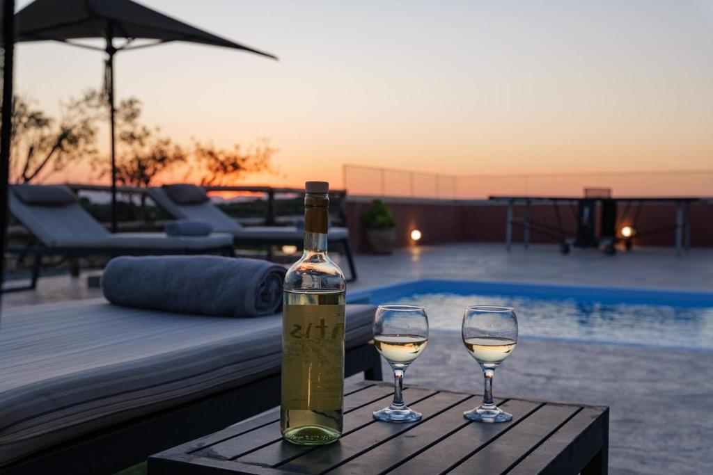 a bottle of wine sitting on a table with two wine glasses at Stavlos Villa - Private Pool in episkopi-heraklion