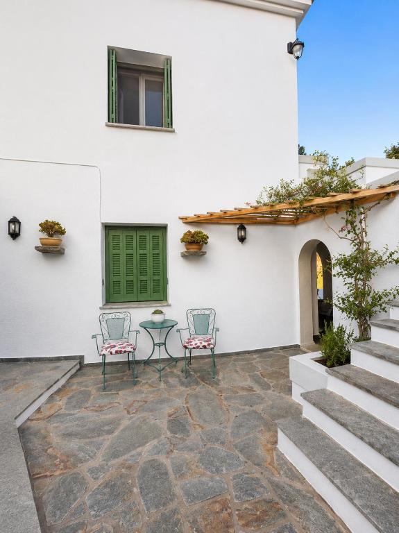 a patio with two chairs and a table in front of a white building at Stellinas Pretty House in Andros