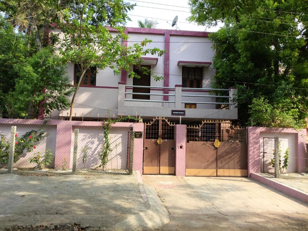 a pink and white house with a gate at Aiswarya illam in Chidambaram