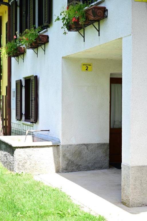 a white building with two potted plants and a door at Apartma Kukč II in Bovec