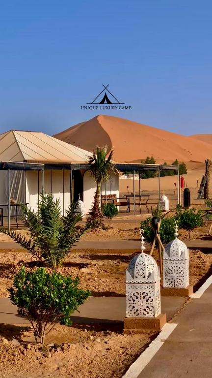 a building in the middle of a desert with trees at Unique Luxury Camp in Merzouga