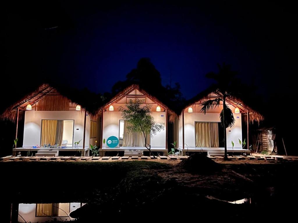 a house lit up at night with lights at Ananda Uthaan in Sreemangal
