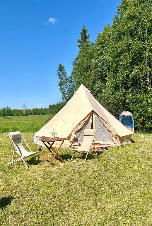 a tent with two chairs and a table in a field at Glamping Arctic Ukuli in Rovaniemi