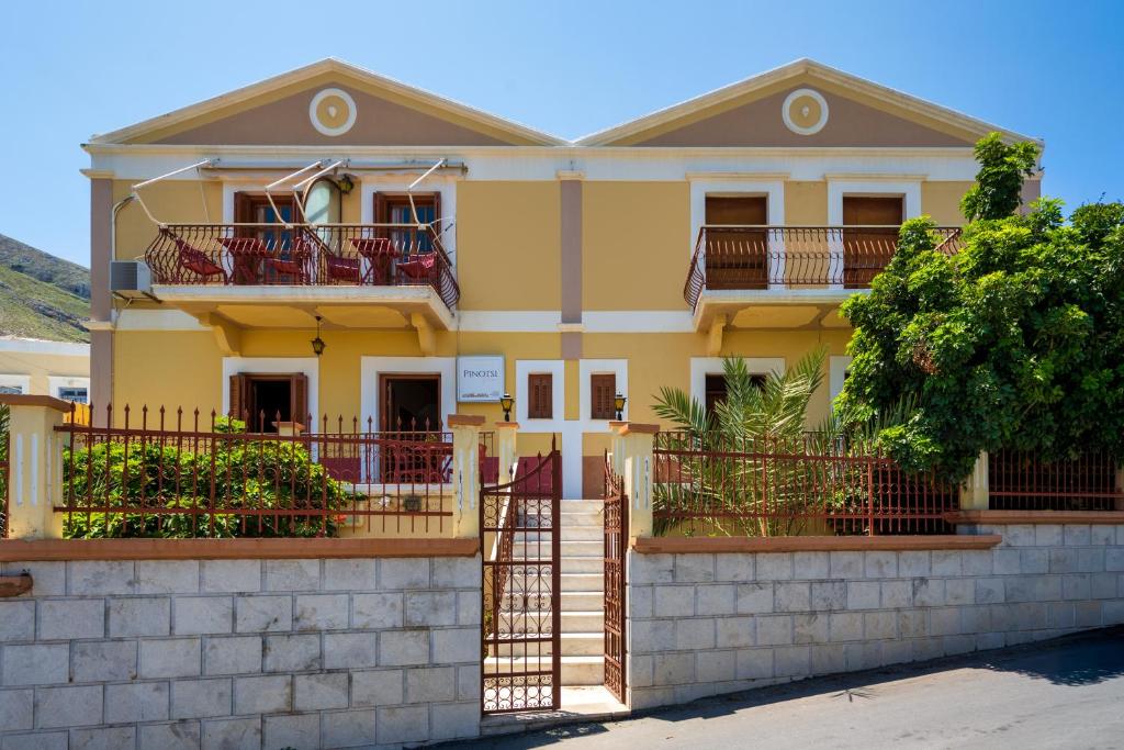 a yellow house with a fence in front of it at Pinotsi Rooms Village Symi in Symi