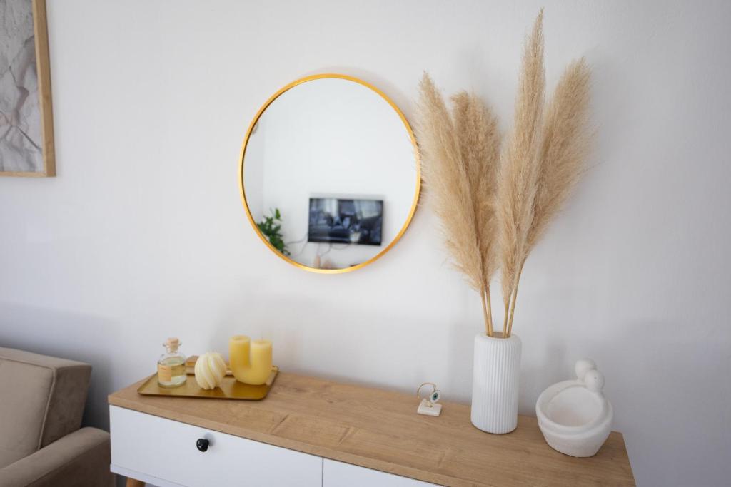 a mirror on a white wall with a table with a vase at Anemoessa in Ammoudia