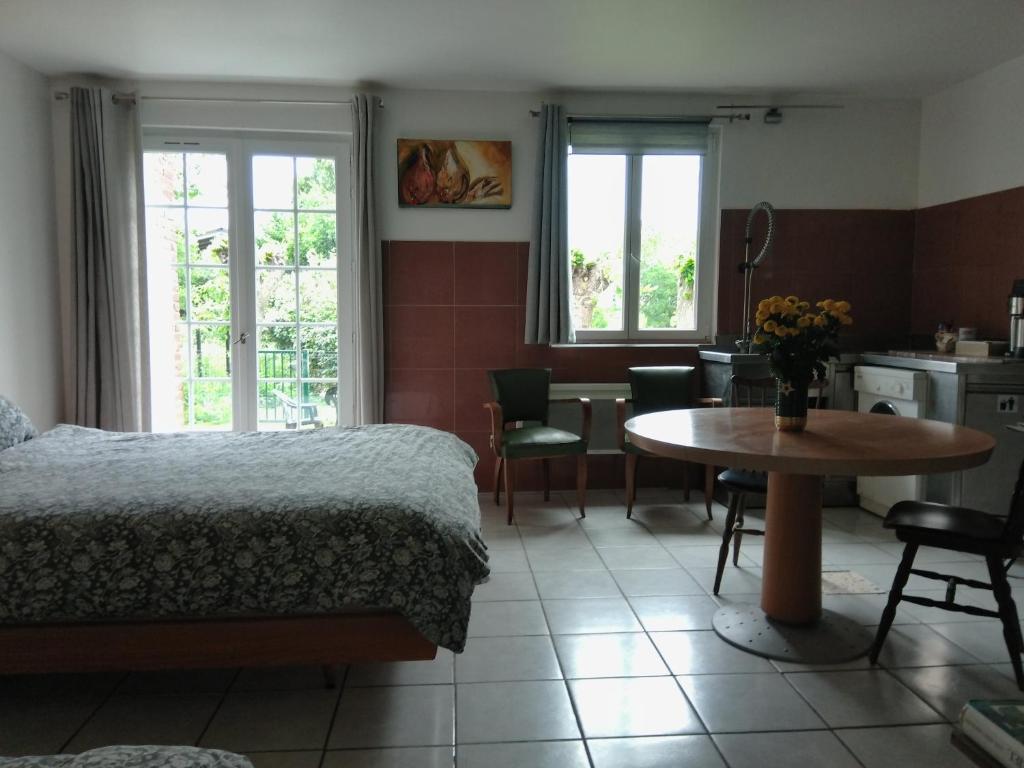 a bedroom with a bed and a table and a kitchen at Logement entier jardin clos parc chien A1 A29 5 mn in Herleville