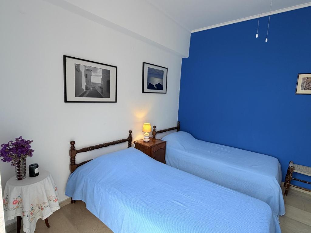 two beds in a room with blue walls at Art & Motion Union - Guest Room 2 in Apoíkia