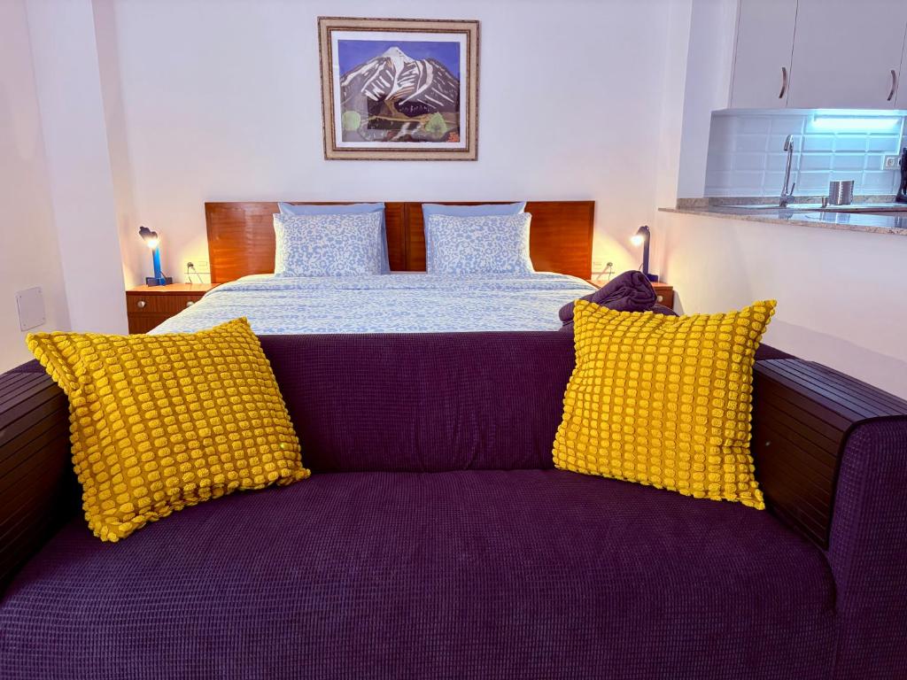 a purple couch with yellow pillows on a bed at Casa Lana - Cozy Beachside Studio in Puertito de Güímar