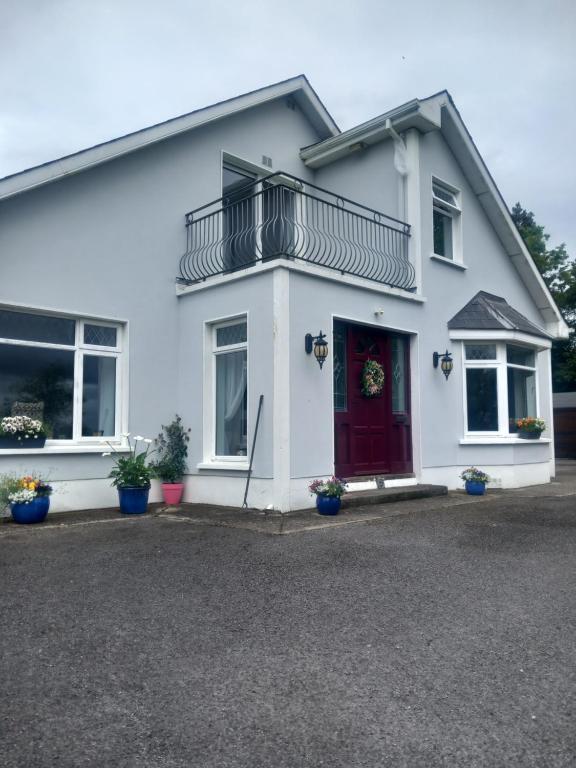 a white house with a red door and a balcony at Waterways Lodge in Carrick on Shannon