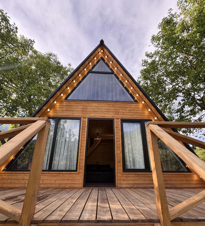 a cabin with a gambrel roof on a wooden deck at Chachkari Cottage in Gogasheni